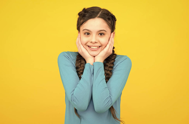 smiling child with long hairdo. cheerful teen with healthy smile. Hair braided in braids. little beauty pleasantly surprised. happy childhood. small girl has nice smile. kid hairstyle fashion - Zdjęcie, obraz