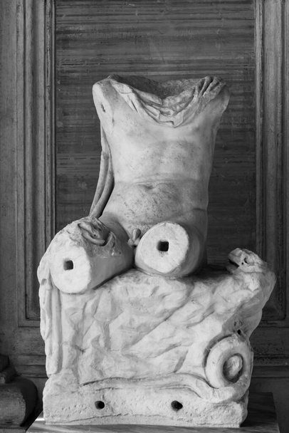 Black and white photo in close-up on ruins of ancient roman statue showing a naked male torso without head and limbs - Photo, Image