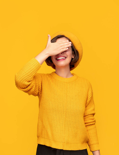Cheerful woman covering eyes with hand - Фото, зображення