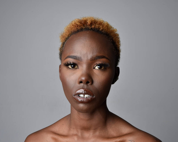 Retrato de cabeza y hombros de una mujer africana joven y bonita con cabello natural. variedad de expresiones faciales emotivas. Aislado sobre un fondo de estudio gris claro. - Foto, Imagen