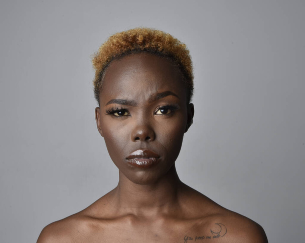 Retrato de cabeza y hombros de una mujer africana joven y bonita con cabello natural. variedad de expresiones faciales emotivas. Aislado sobre un fondo de estudio gris claro. - Foto, imagen
