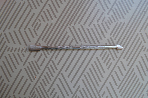 Железная палка для маникюра на столе с серым рисунком - Фото, изображение