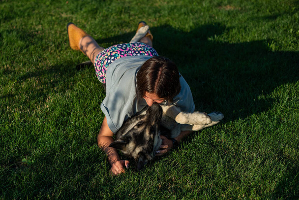 Schattig tienermeisje die een Duitse herdershond knuffelt. Schattige jonge vrouw met een puppy hond in de natuur. - Foto, afbeelding