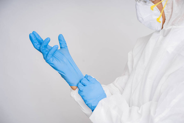 Doctor in a protective suit puts on blue rubber gloves. - Fotó, kép