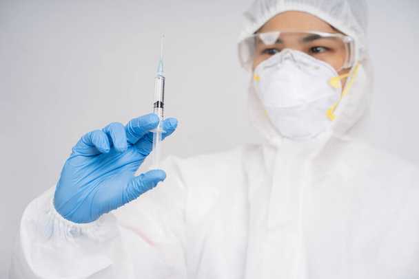 A tudósok védőruházatot viselnek, miközben fecskendőt használnak a vírusos gyógyszerek laboratóriumi vizsgálatához.. - Fotó, kép