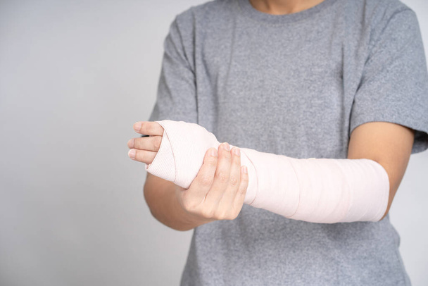 Азиат держит сломанную руку в студии, несчастный случай дома, травма. - Фото, изображение