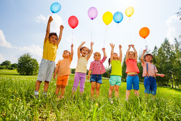 Happy kids with balloons and arms up in the sky - Foto, immagini