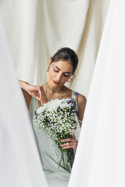 brunette woman looking at bouquet of flowers on white - 写真・画像