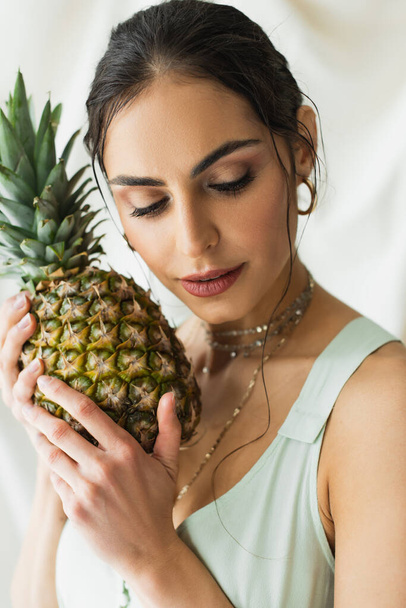 brunette model posing near ripe pineapple on white - Fotografie, Obrázek