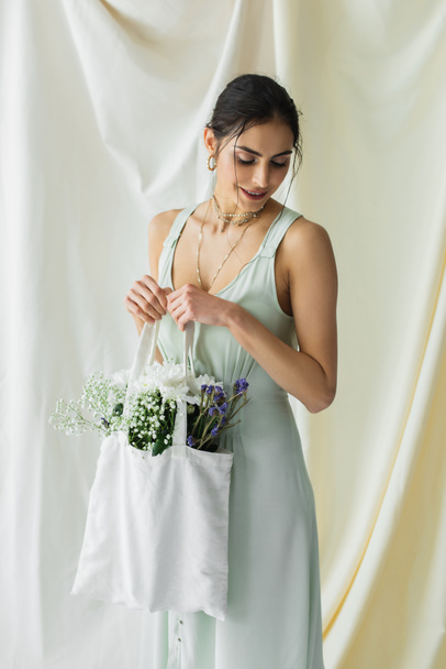 happy woman holding fabric shopper bag with flowers on white - Photo, Image