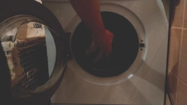 Мужчина дома достает чистый белый лист из стиральной машины. Концепция мужской чистоты и стирки - Кадры, видео
