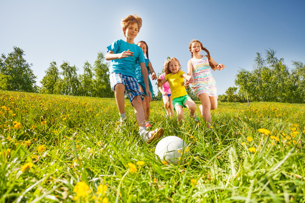 Happy kids playing football in green field - Zdjęcie, obraz