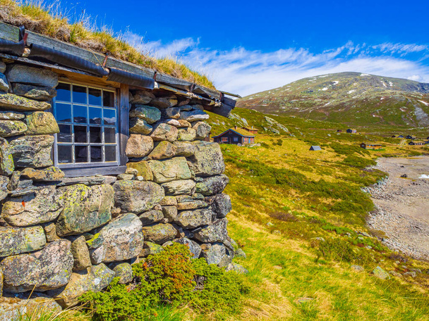 Amazing Vavatn lake panorama rough landscape view cottages and mountains with snow during summer in Hemsedal Norway. - Foto, afbeelding
