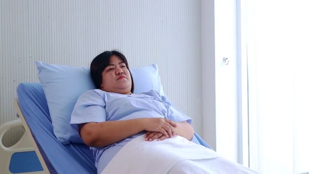 asiatico grasso donna sdraiata in ospedale letto sentimento stressato per il malattia, mettere il mano su il fronte. concetto di problemi sanitari per le persone obese, assicurazione sanitaria, spazio copia - Filmati, video
