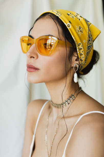 stílusos nő divatos napszemüveg és sárga fejkendő pózol fehér - Fotó, kép