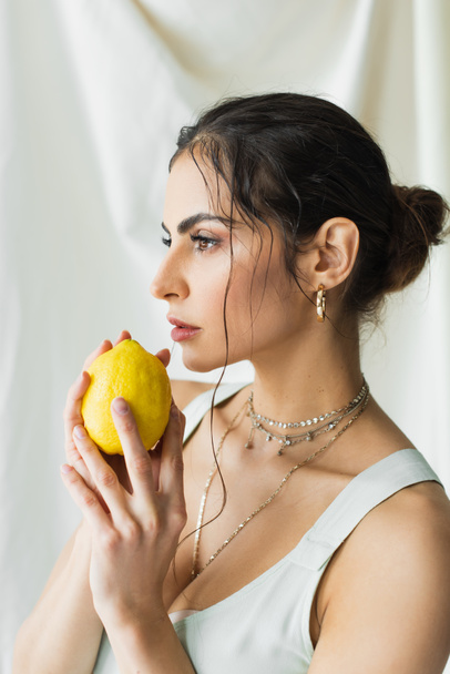 pretty woman in dress holding fresh lemon on white - Fotó, kép