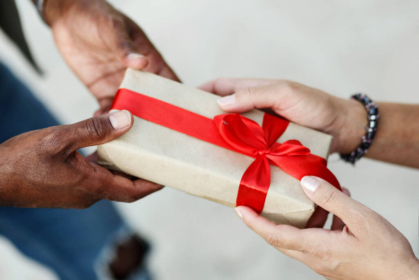 Sluit de handen van een interraciaal stel. Man geeft Valentijnsdag cadeau aan zijn vrouw, vriendin of vrouw - Foto, afbeelding