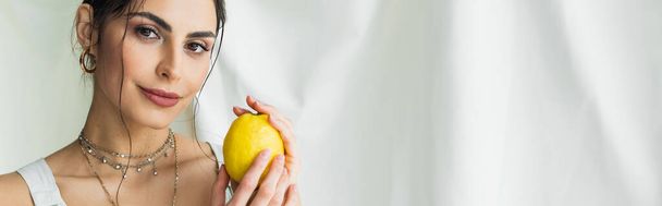 Улыбающаяся женщина держит свежий лимон на белом, баннер - Фото, изображение