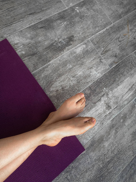 A high angle shot of female feet on a purple mat - Fotografie, Obrázek