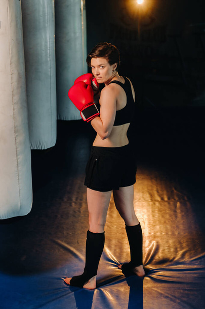 portrait of a female boxer in red gloves in the gym during training. - Photo, Image