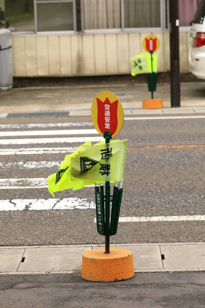 κίτρινες σημαίες διέλευσης πεζών, με διάβαση πεζών έτοιμη για χρήση στη λίμνη Ιναβασίρο. Το 'Crossing' είναι γραμμένο στα Ιαπωνικά.. - Φωτογραφία, εικόνα