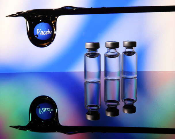 Pieni rokotepullo läpinäkyvä heijastus taittuminen sininen led-valo taustalla hypoderminen ruisku neula pisara tyyppi covid 19 rokote - Valokuva, kuva