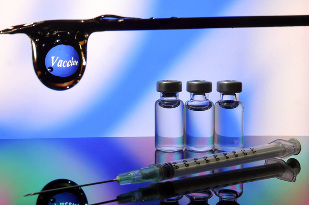 Kleine vaccin injectiefles transparant reflectie breking blauw led licht achtergrond hypodermische spuit naalddruppel type covid 19 vaccin - Foto, afbeelding