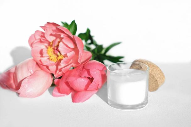 white scented candle and red peony flowers. home fragrances for cozy atmosphere. flower fragrance for home. unbranded ceramic candle - Valokuva, kuva