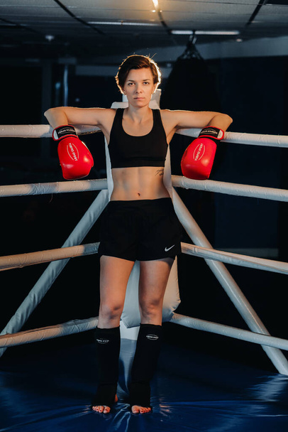 portrait of a female boxer in red gloves in the gym during training. - Foto, imagen