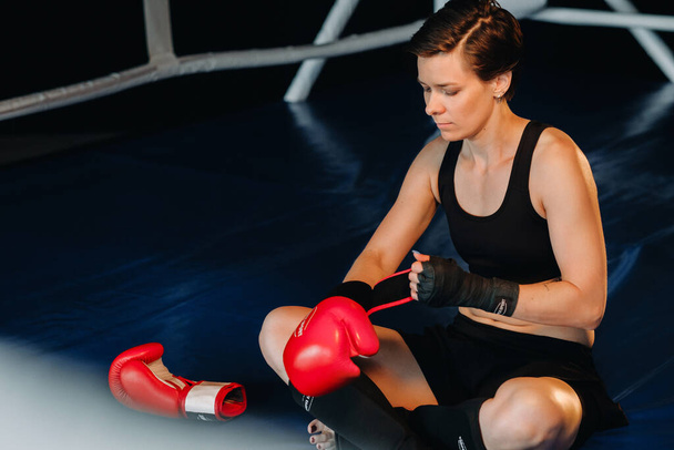 portrait of a female boxer in red gloves in the gym during training. - Foto, afbeelding