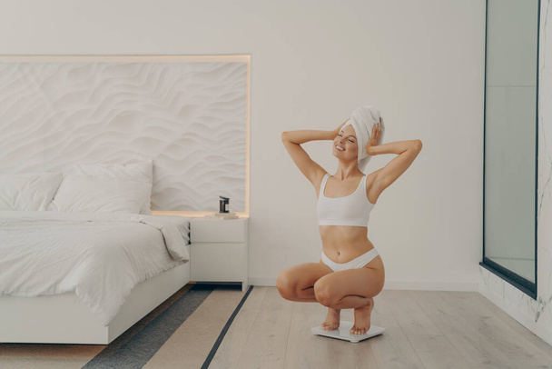 piękne młody pasuje kobieta model przysiady na wagi w nowoczesny sypialnia wnętrze - Zdjęcie, obraz