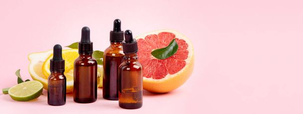 Bottles of essential aroma oils with citrus on pink background. Panorama - Foto, immagini