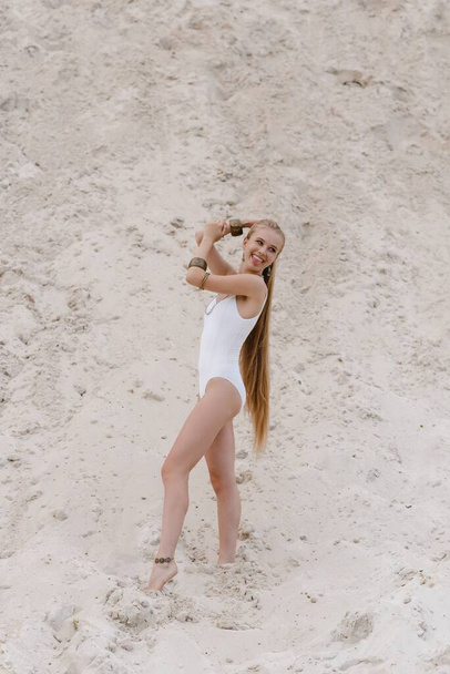 若いです細い美しいですスリムセクシー女性でホワイト水着ボディスーツ上の白い砂の上にビーチとともに - 写真・画像