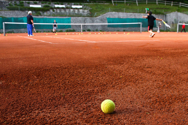 Lapset pelaavat tennistä. Yksinäinen pallo makaa heidän edessään.
. - Valokuva, kuva