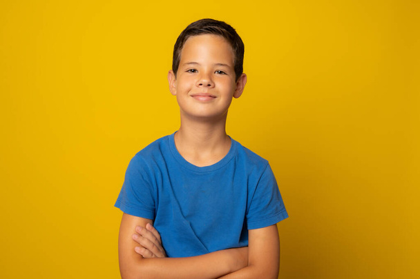 Retrato de um menino de escola feliz com os braços cruzados, isolado em amarelo. - Foto, Imagem