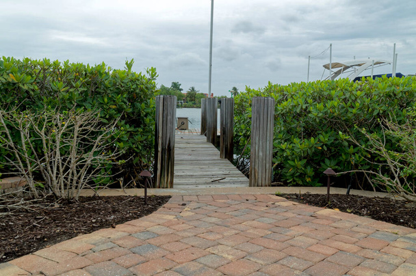 Uma passarela pavimentada leva a uma doca de madeira cercada por manguezais em um dia nublado na Flórida. - Foto, Imagem