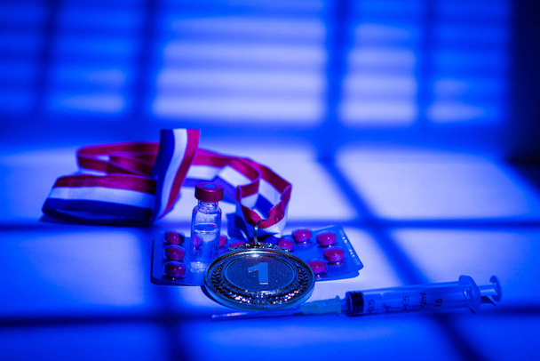 Zlatá medaile šampiona, injekční stříkačka s dopingovou látkou, pilulka a lahvička se zakázanou látkou se světly a stíny závěsu, která v noci vstupuje oknem. Sportovní a dopingový koncept - Fotografie, Obrázek