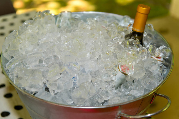 A bottle of wine and beer bottles buried in an ice bucket. - Photo, Image