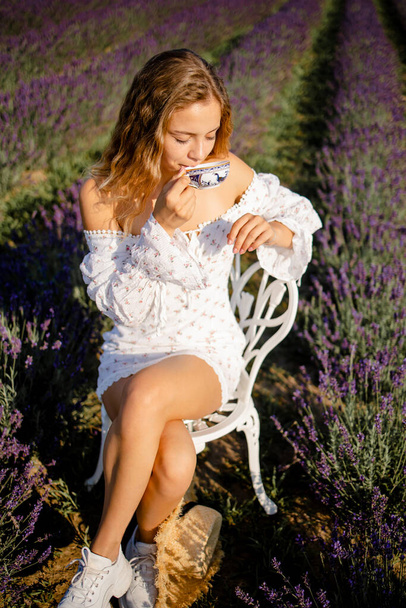 Pretty Blonde Woman Drinking Tea In Lavender Field In Summer Morning. - Zdjęcie, obraz