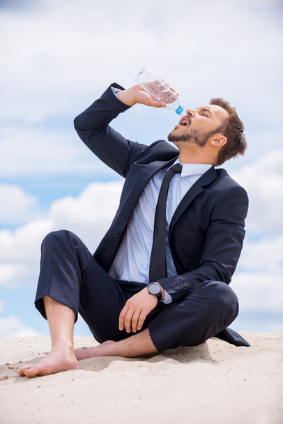 Businessman drinking water on top of sand dune - Zdjęcie, obraz