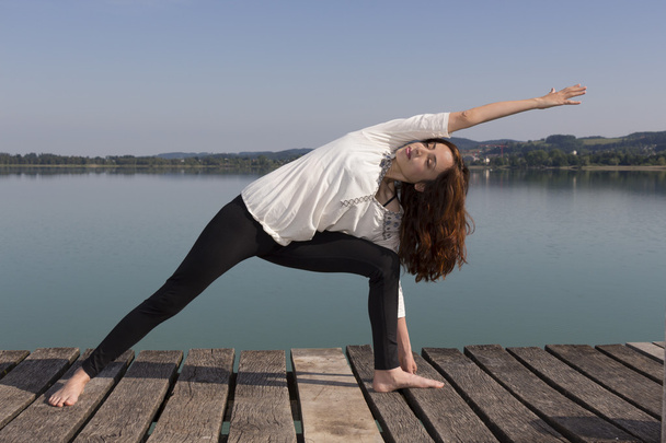 Woman doing Extended side angle pose in yoga in nature - Photo, Image