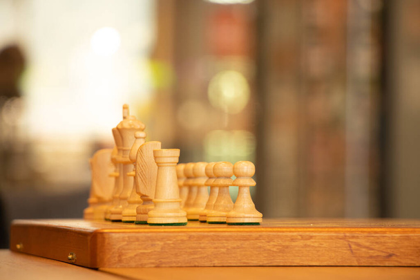 braunes Schachbrett mit Figuren auf einem Holztisch in einem Café beim Schachspielen - Foto, Bild