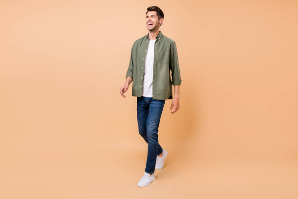 Photo of funny handsome young gentleman wear khaki shirt walking laughing smiling isolated beige color background - Fotografie, Obrázek