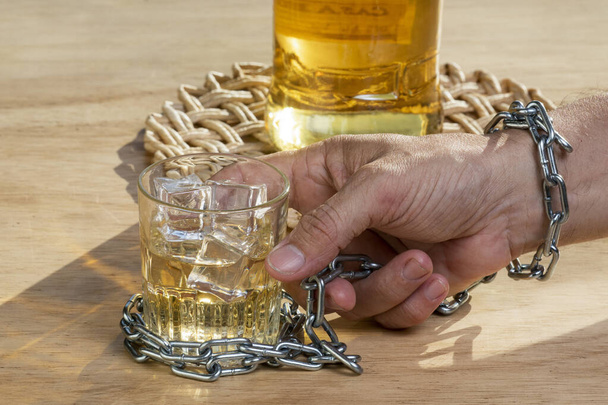 Hands lock chain a glass of whiskey to stop drinking. Alcoholism concept. Stop alcohol addiction drink. - Photo, Image