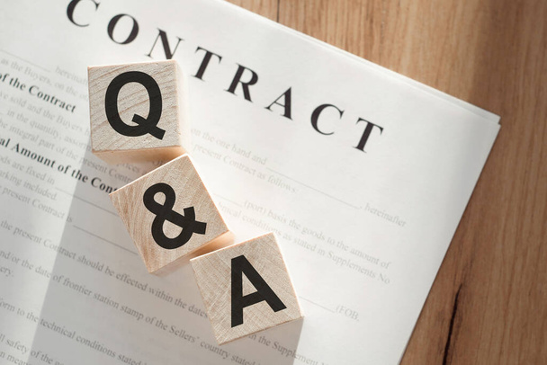 Word Q&A question and answer, on wooden cubes on contract documents background. - Zdjęcie, obraz