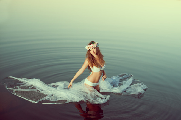 Beautiful woman in a lake at night. Girl at sunset in the lake. - Foto, afbeelding