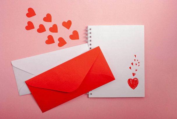 Notebook with a drawing of a heart, envelopes, red hearts on a pink background. - Fotoğraf, Görsel