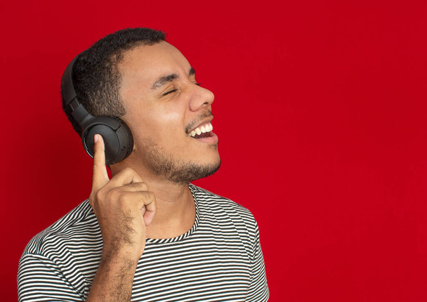 muž těší a poslech na sluchátka s červeným pozadím - Fotografie, Obrázek