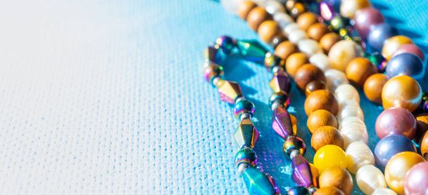 Un mucchio di perline di gioielli luminosi colorati su uno sfondo blu. Collana di perline di gemme diverse. Collana gioiello modello di moda moderna o texture. Spazio per il testo. Foto di alta qualità - Foto, immagini