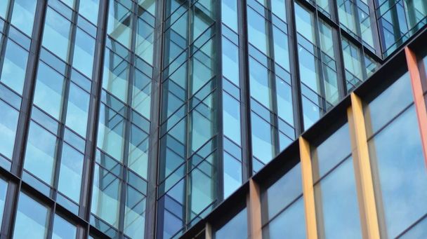 La fachada acristalada de un edificio de oficinas con cielo reflejado. Edificios de arquitectura moderna exterior  - Foto, imagen